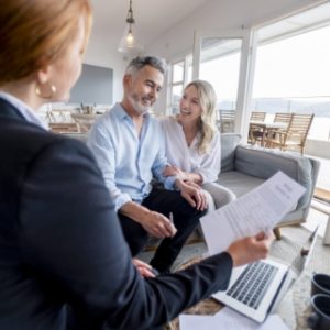 Un homme et une femme sourient à une conseillère pendant une réunion à la maison.