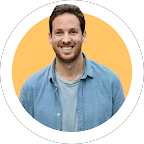 Homme souriant portant une chemise en denim, fond orange clair.