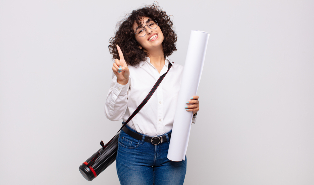 Femme souriante avec des lunettes, tenant un rouleau de papier et levant un doigt.